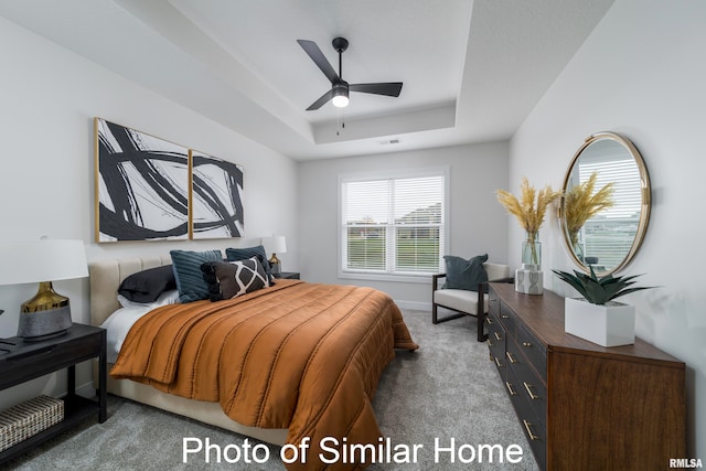 bedroom featuring a raised ceiling, carpet flooring, and ceiling fan