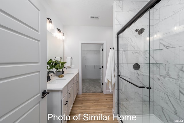 bathroom with vanity, hardwood / wood-style floors, and a shower with door