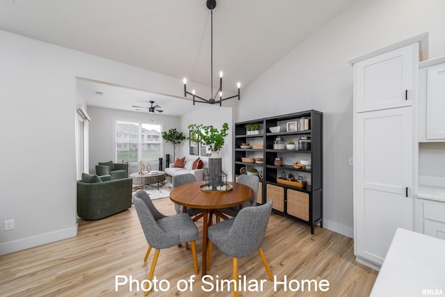 dining area with vaulted ceiling, light wood-type flooring, and ceiling fan with notable chandelier