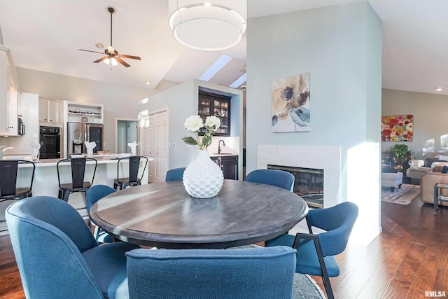 dining area with sink, dark wood-type flooring, high vaulted ceiling, and ceiling fan