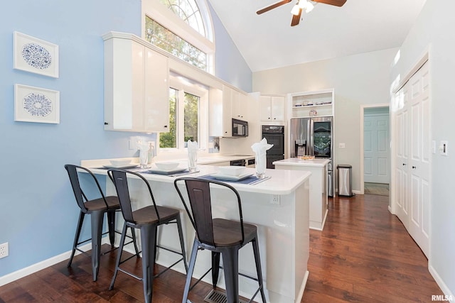 kitchen with a breakfast bar area, kitchen peninsula, white cabinetry, and dark hardwood / wood-style flooring