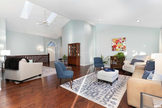 living room with ceiling fan, a textured ceiling, high vaulted ceiling, dark wood-type flooring, and a skylight