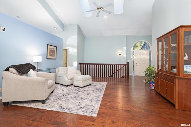 living room with a skylight, ceiling fan, high vaulted ceiling, and dark hardwood / wood-style flooring