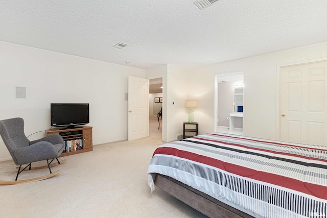 bedroom featuring light carpet, a textured ceiling, and connected bathroom