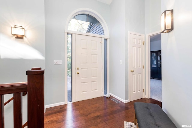 entryway featuring dark wood-type flooring and a towering ceiling