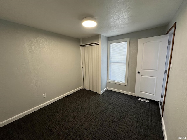 unfurnished bedroom featuring dark colored carpet, baseboards, and a closet