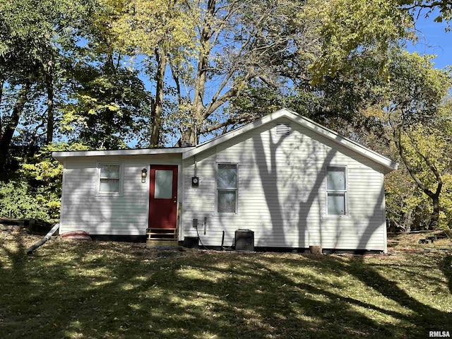 back of property with cooling unit, entry steps, and a lawn