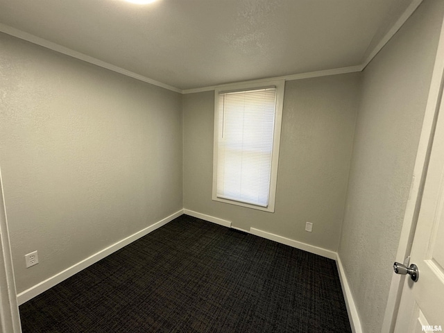 spare room with dark carpet, crown molding, and baseboards