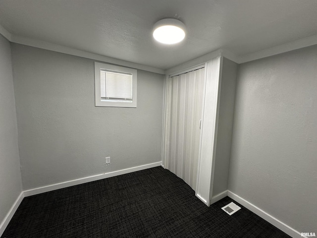 unfurnished bedroom with dark carpet, baseboards, visible vents, and a closet