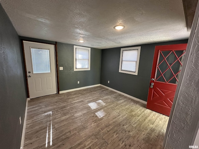 entryway featuring baseboards, wood finished floors, and a textured ceiling
