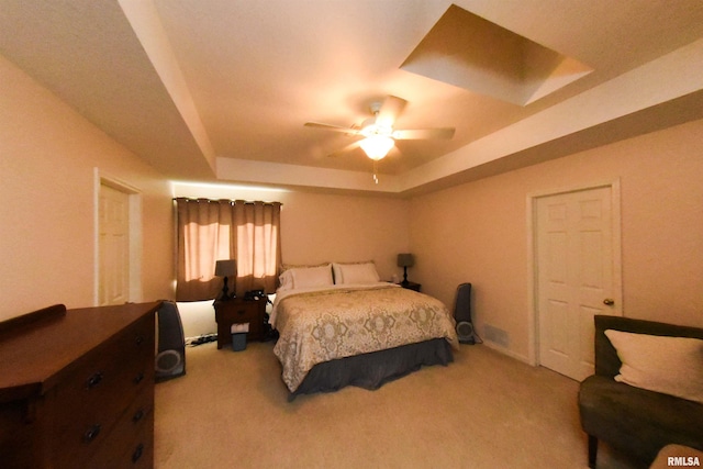 carpeted bedroom with ceiling fan and a tray ceiling