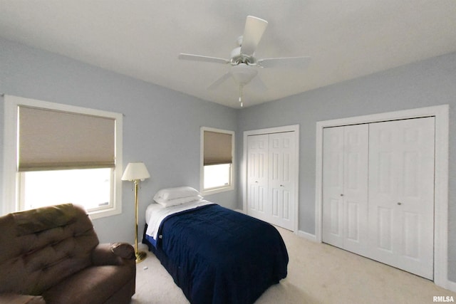 carpeted bedroom featuring multiple closets and ceiling fan