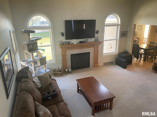 carpeted living room with a high ceiling and a fireplace