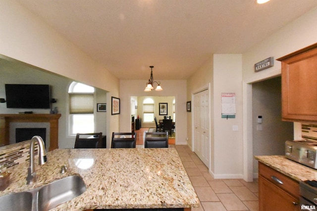 kitchen with light stone counters, a chandelier, light tile patterned flooring, sink, and decorative light fixtures