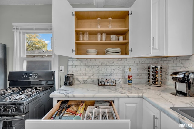 kitchen with light stone countertops, black range with gas cooktop, decorative backsplash, and white cabinetry