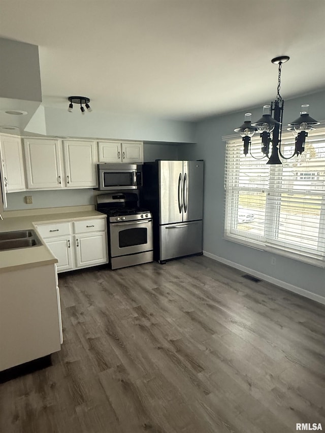 kitchen with sink, hanging light fixtures, stainless steel appliances, a chandelier, and white cabinets