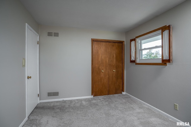 unfurnished bedroom with light carpet and a closet