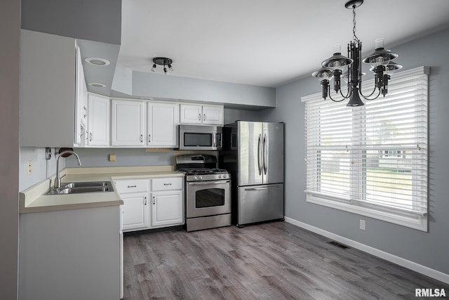 kitchen with white cabinetry, sink, a chandelier, decorative light fixtures, and appliances with stainless steel finishes