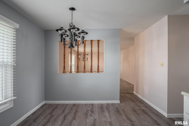 unfurnished dining area with plenty of natural light, hardwood / wood-style floors, and a notable chandelier