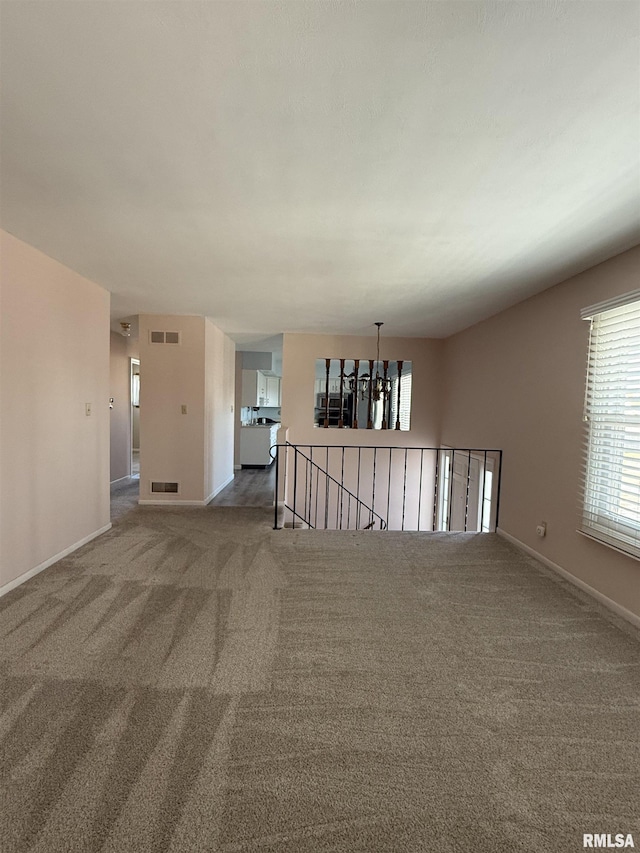 carpeted spare room with a chandelier