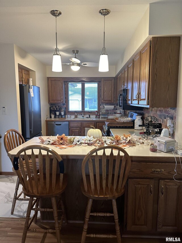 kitchen with a breakfast bar, dishwashing machine, freestanding refrigerator, tasteful backsplash, and range