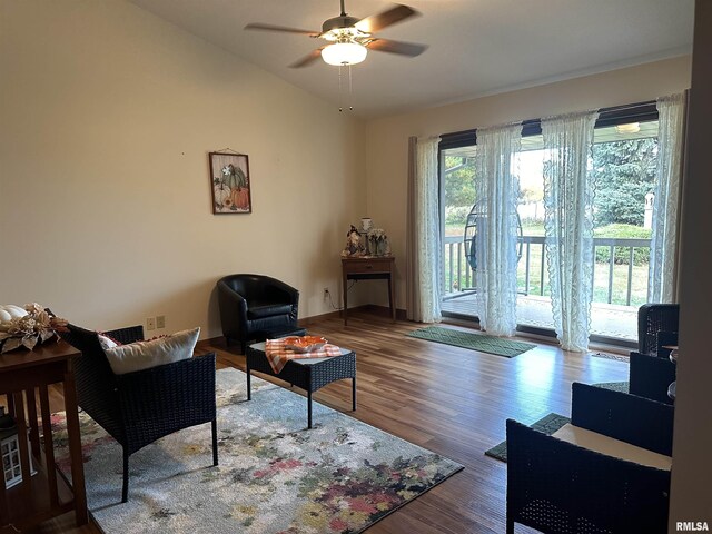 living area with lofted ceiling, wood finished floors, baseboards, and ceiling fan