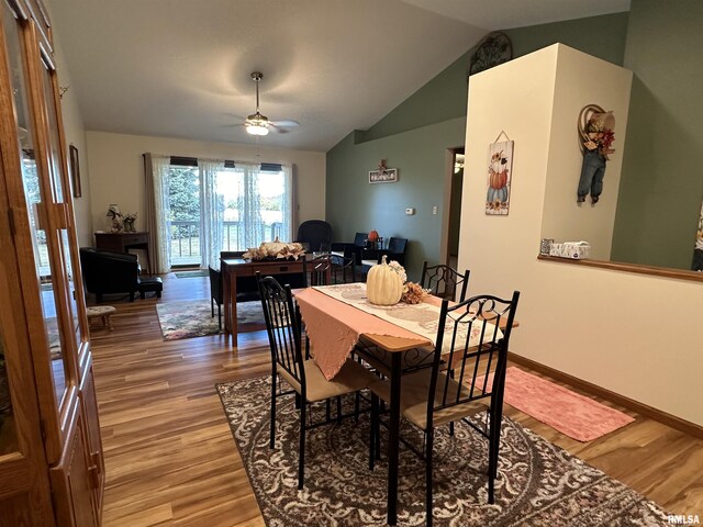 dining space with vaulted ceiling, a ceiling fan, light wood-style floors, and baseboards