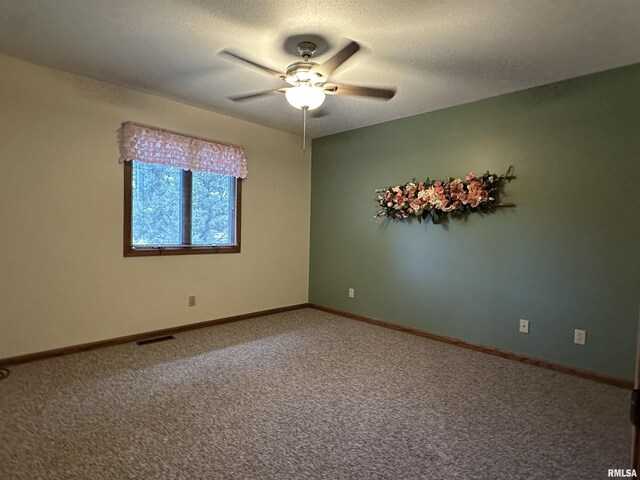 spare room featuring baseboards, a ceiling fan, visible vents, and carpet