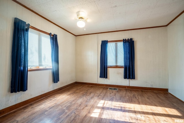 spare room featuring wood-type flooring and crown molding