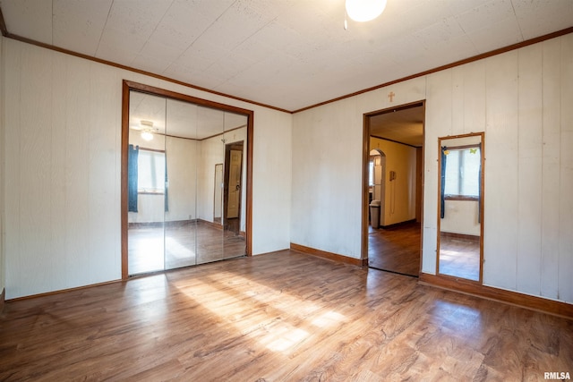 unfurnished bedroom featuring hardwood / wood-style flooring, ornamental molding, and a closet