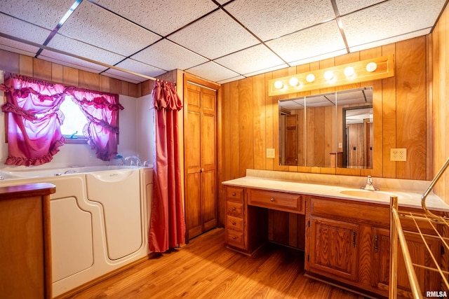 bathroom featuring a paneled ceiling, vanity, washer and clothes dryer, wood-type flooring, and wood walls