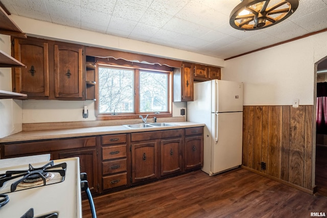 kitchen with dark hardwood / wood-style flooring, white appliances, crown molding, wooden walls, and sink