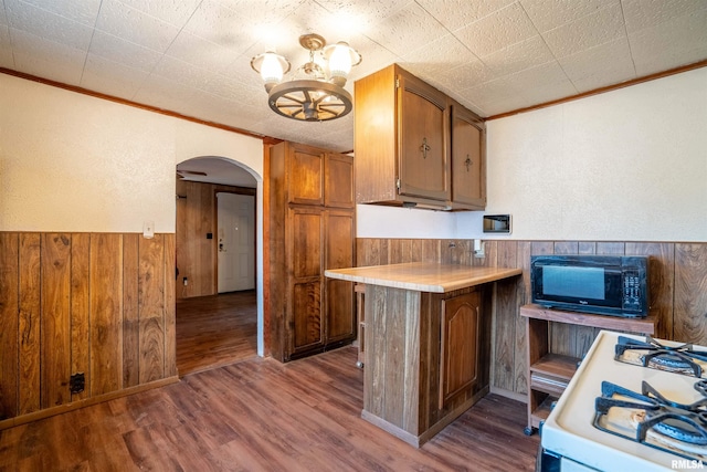 kitchen featuring hardwood / wood-style floors, ornamental molding, white gas range oven, and a chandelier