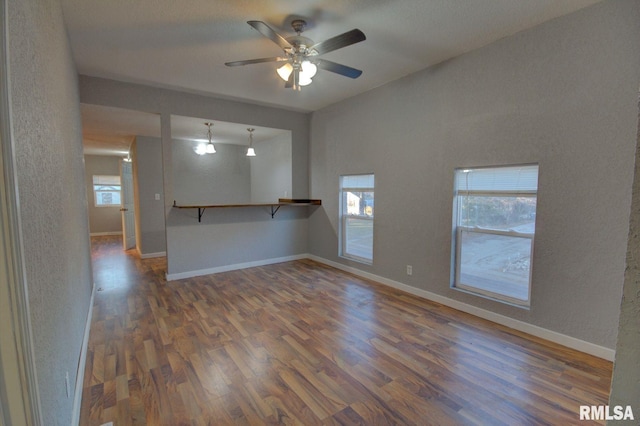 spare room with ceiling fan, plenty of natural light, and dark wood-type flooring