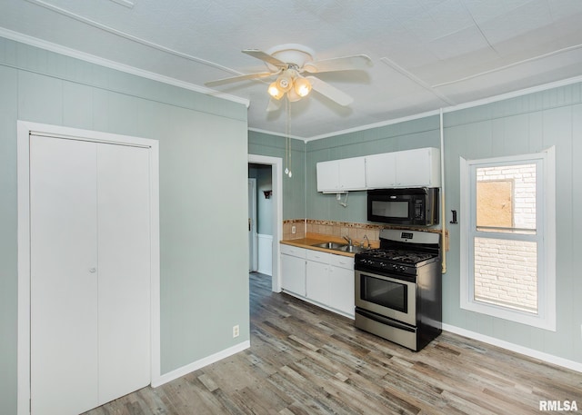 kitchen with light wood-type flooring, ornamental molding, white cabinetry, gas range, and decorative backsplash