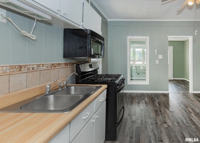 kitchen featuring white cabinets, ornamental molding, black appliances, dark wood-type flooring, and sink