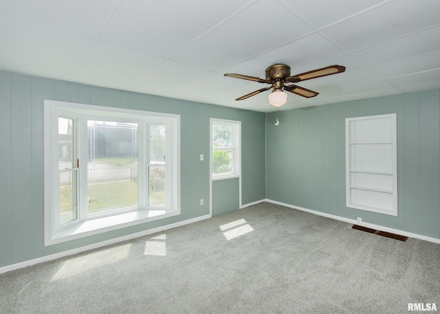 spare room featuring built in shelves, carpet flooring, and ceiling fan