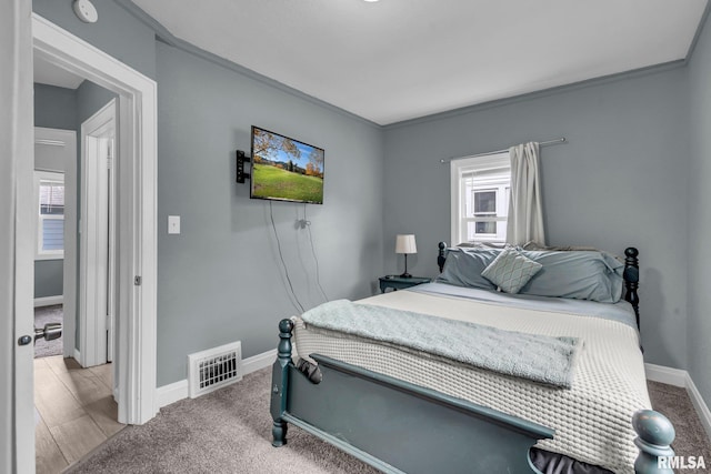 bedroom featuring crown molding, multiple windows, and light colored carpet