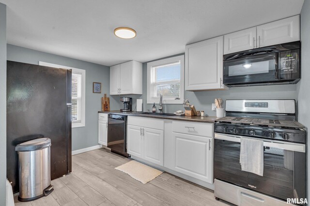235 W 32nd St, Davenport, IA 52803 - kitchen with black appliances, light wood-style flooring, white cabinetry, and plenty of natural light