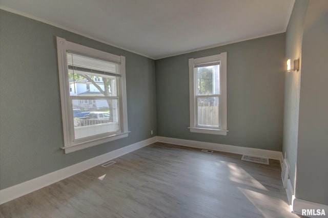 unfurnished room featuring a wealth of natural light, crown molding, and light hardwood / wood-style floors