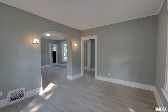 empty room with light hardwood / wood-style flooring and crown molding