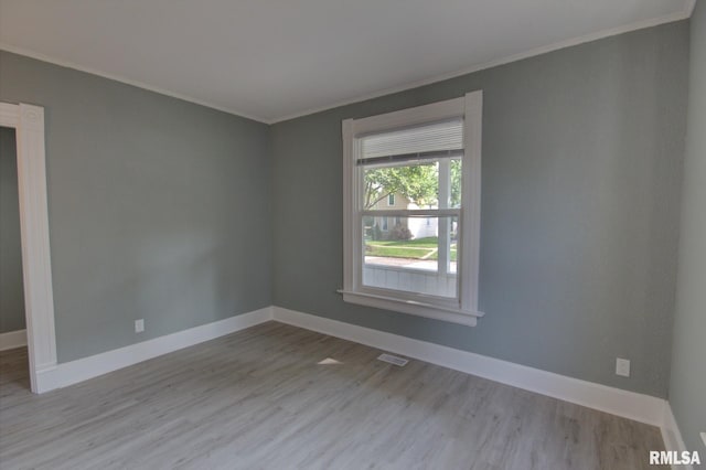 spare room featuring crown molding and light wood-type flooring