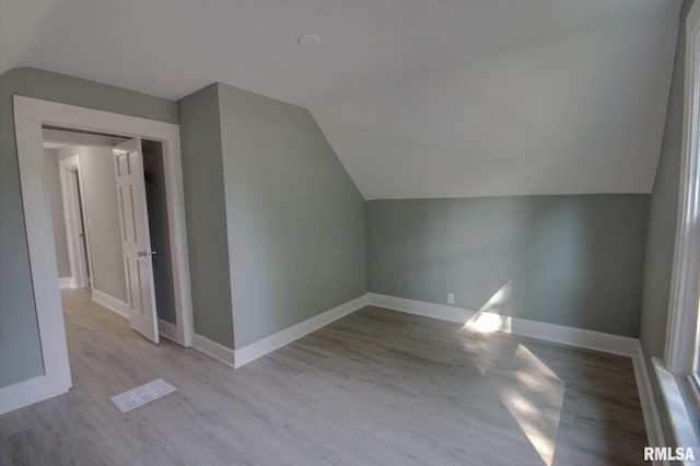 bonus room with vaulted ceiling and light wood-type flooring