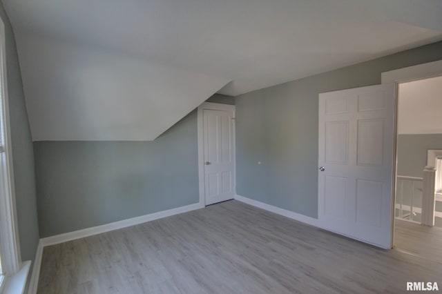 additional living space featuring lofted ceiling and light wood-type flooring