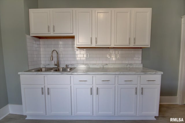 kitchen with white cabinetry, sink, wood-type flooring, and backsplash