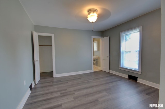 unfurnished bedroom featuring connected bathroom, light hardwood / wood-style floors, and ceiling fan