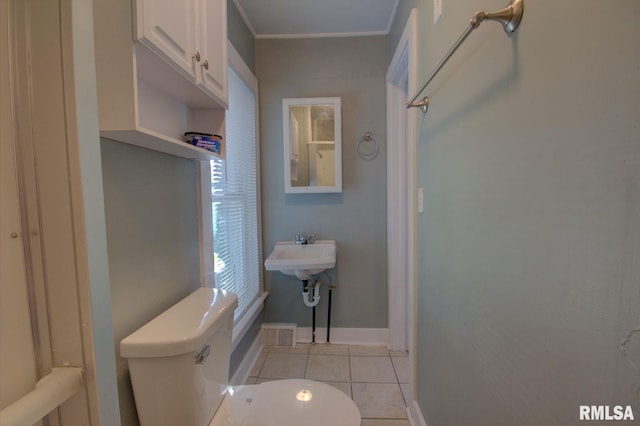 bathroom with toilet, sink, and tile patterned flooring