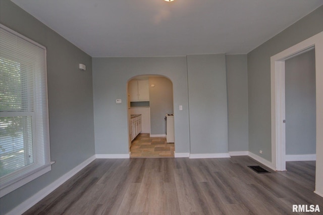 empty room with hardwood / wood-style floors and a healthy amount of sunlight