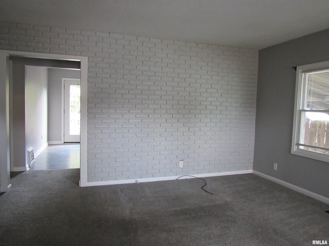 carpeted empty room with brick wall