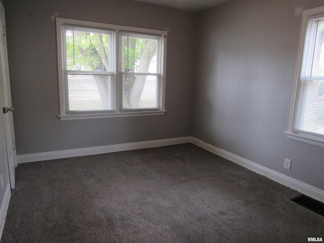 spare room with dark carpet and plenty of natural light